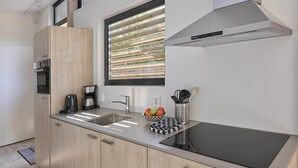 Eine moderne Küche mit Einbauherd, Kaffeemaschine und Obstschale auf der Arbeitsfläche.