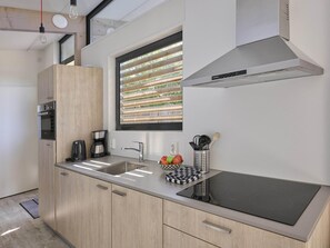 A modern kitchen with a built-in stove, a coffee maker, and a fruit bowl on the counter. - Beach lodge on the beach (Callantsoog)