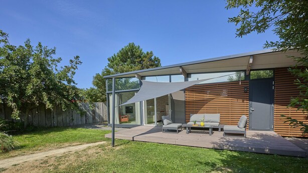 Eine moderne Terrassengestaltung mit Glasverkleidung, Holzlamellen und Gartenmöbeln.