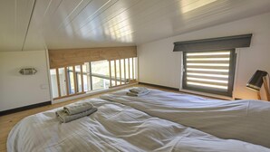 Un dormitorio con dos camas, una ventana con persianas, un ventilador de techo y vistas al exterior.