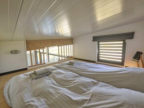 Ein Schlafzimmer mit zwei Betten, einem Fenster mit Jalousien, einem Deckenventilator und Blick ins Freie.