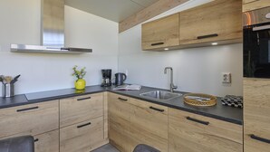 Una cocina moderna con armarios de madera, un lavamanos de acero inoxidable y un horno empotrado.