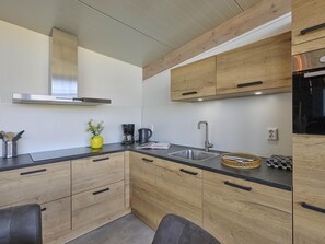 Eine moderne Küche mit Holzschränken, einer Edelstahlspüle und einem eingebauten Backofen.