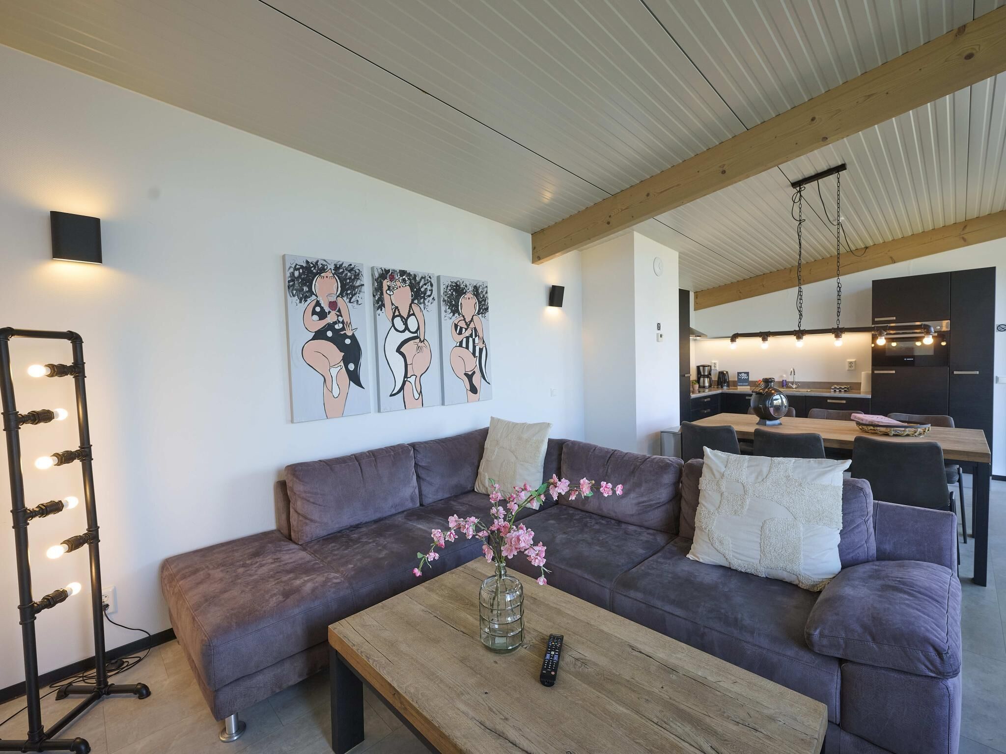 Una sala de estar moderna con un sofá, una mesa de centro con un jarrón de flores y una lámpara de pared.