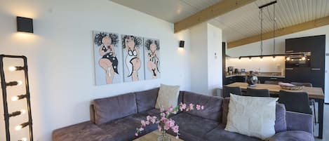 En moderne stue med en sofa, et sofabord med en vase blomster og en vægmonteret lampe.