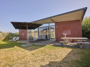 Ein moderner Außenbereich mit Terrasse, überdachter Sitzgruppe, Holzdeck und Picknicktisch.