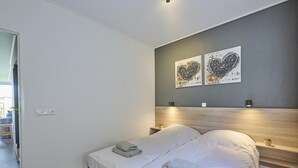 A modern bedroom with a bed, bedside tables, and wall art. - Holiday home 350 meters from the beach (Callantsoog)