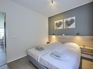 A modern bedroom with a bed, bedside tables, and wall art. - Holiday home 350 meters from the beach (Callantsoog)