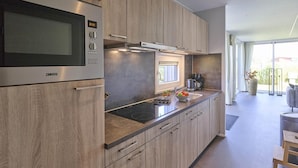 A modern kitchen with a built-in stove, microwave, and a window above the sink. - Holiday home 350 meters from the beach (Callantsoog)