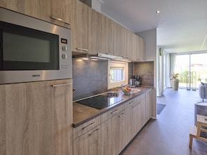 A modern kitchen with a built-in stove, microwave, and a window above the sink. - Holiday home 350 meters from the beach (Callantsoog)