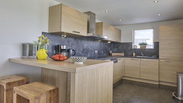 A modern kitchen with wooden cabinets, a central island, and a window providing natural light. - Delightful detached beach villa (Callantsoog)