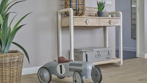 A vintage toy car, a wicker plant, and a wooden shelf with a suitcase and a welcome sign. - Delightful detached beach villa (Callantsoog)