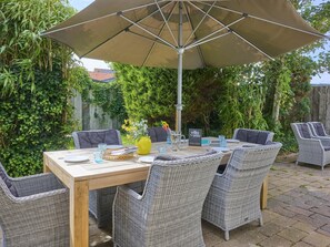 Un patio al aire libre con una mesa y sillas, rodeado de vegetación.