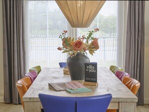 Una mesa de comedor con un florero, un libro titulado 'VILLA for you' y un letrero con el mismo título.