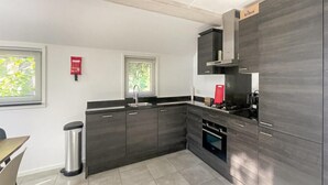 Een moderne keuken met donkere kastjes, een roestvrijstalen spoelbak en een inbouwoven.
