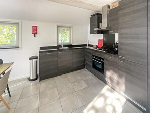 A modern kitchen with dark cabinetry, a stainless steel sink, and a built-in oven. - Nice 8-person house in a child-friendly park. (Otterlo)