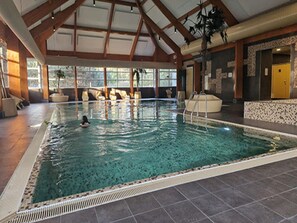 An indoor swimming pool with a tiled floor, a lifeguard chair, and a pool ladder. - Nice 8-person house in a child-friendly park. (Otterlo)