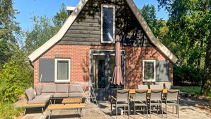 Een huis met een puntgevel, een bakstenen gevel en een terras met tuinmeubilair.