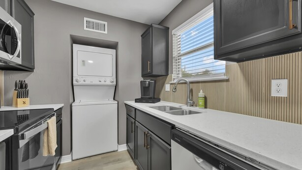A modern kitchen with a microwave, refrigerator, coffee maker, and dishwasher. - Dallas: Walk to Texas A&M Campus, Comfy King Beds (Bryan)