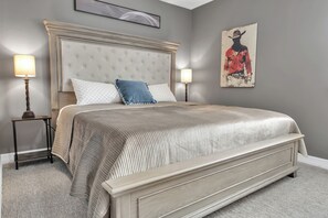 Une chambre à coucher avec un grand lit, deux tables de chevet, une tête de lit et une œuvre d’art accrochée au mur.