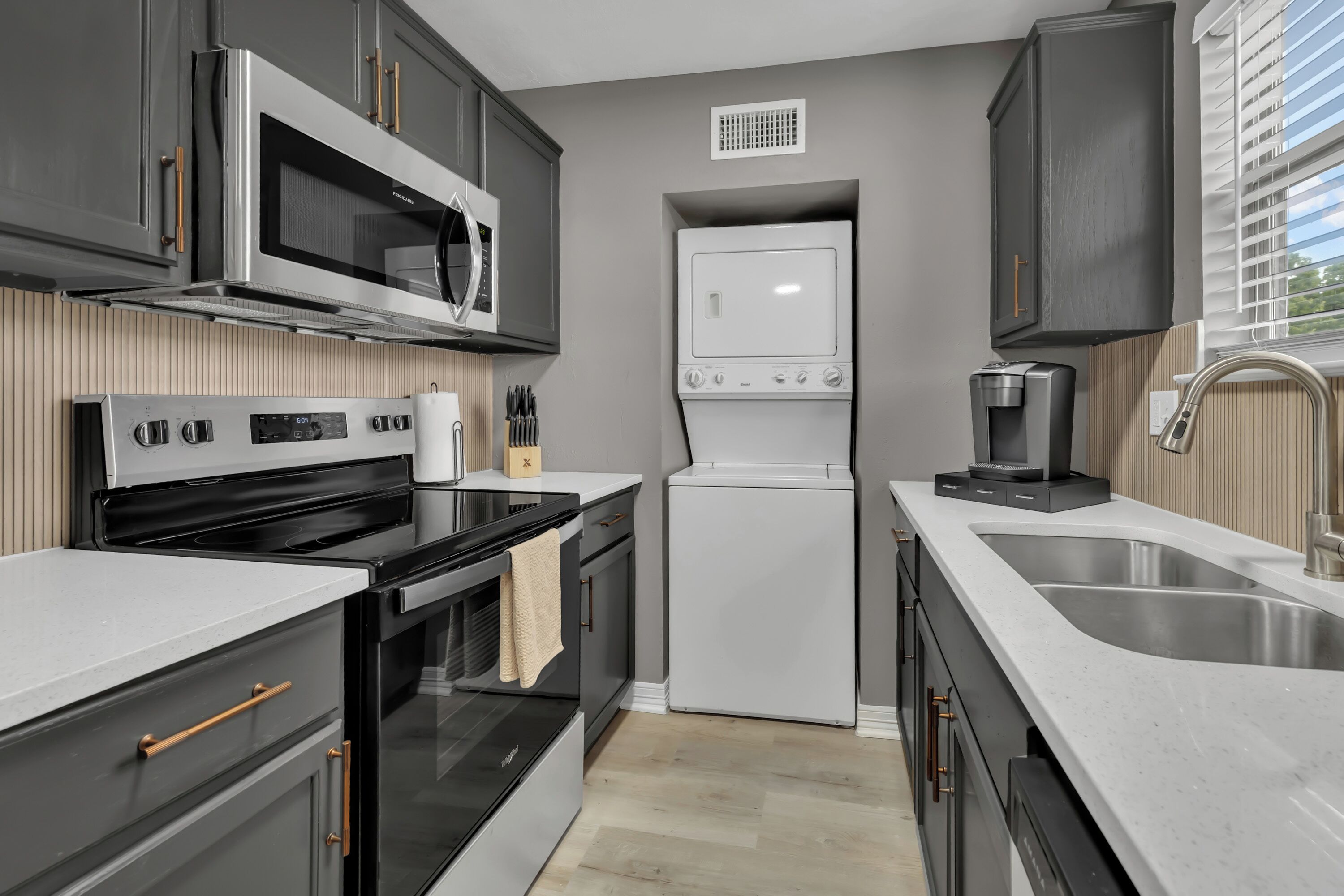 A modern kitchen with a built-in oven, microwave, and a compact refrigerator.