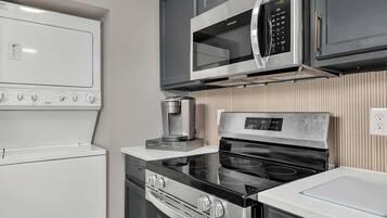 A compact kitchen with a microwave, oven, stovetop, and coffee maker.