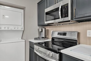 Cocina compacta equipada con microondas, horno, cocina y cafetera.