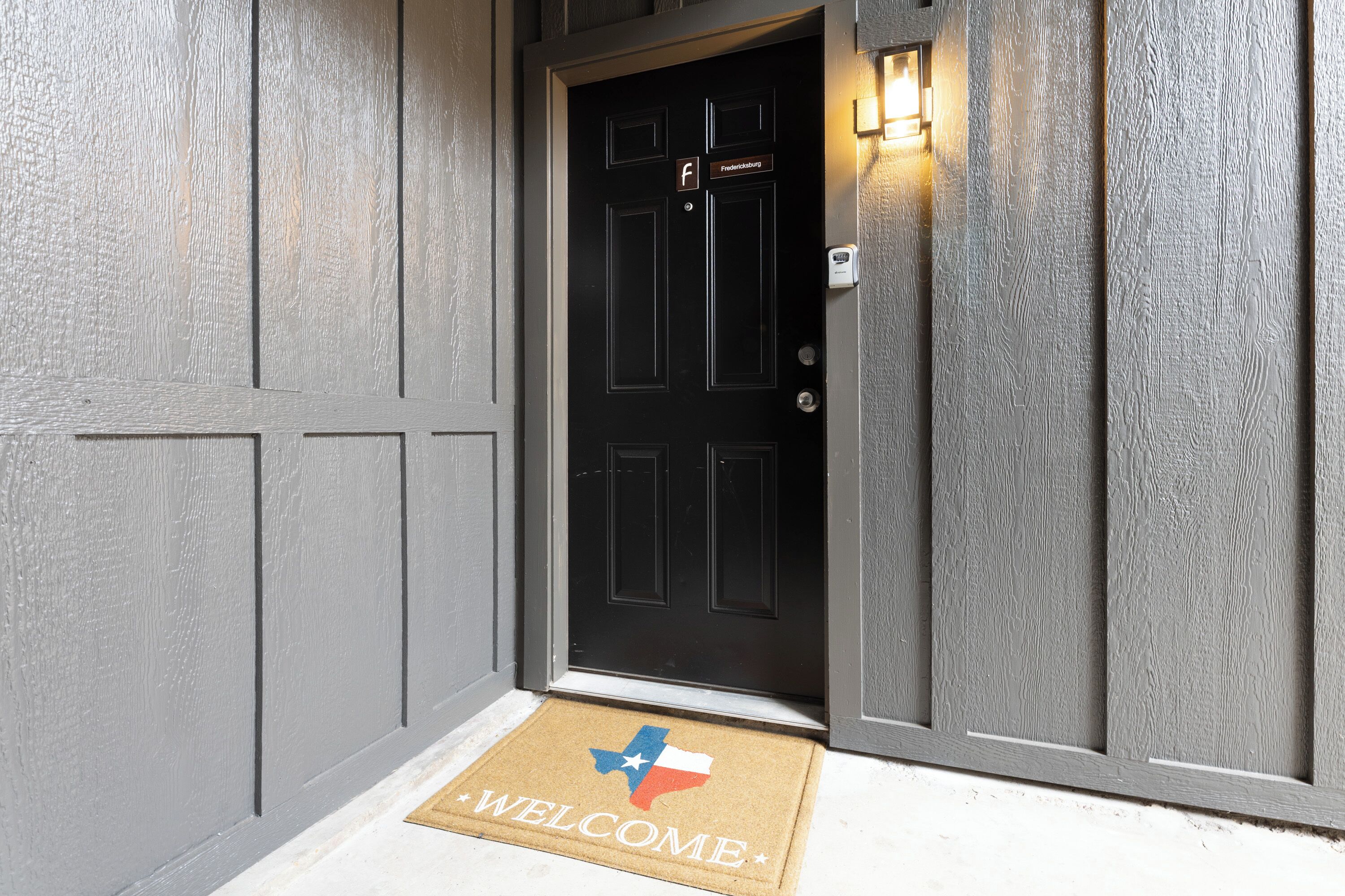 A door with a 'Welcome' mat and a light fixture above it.
