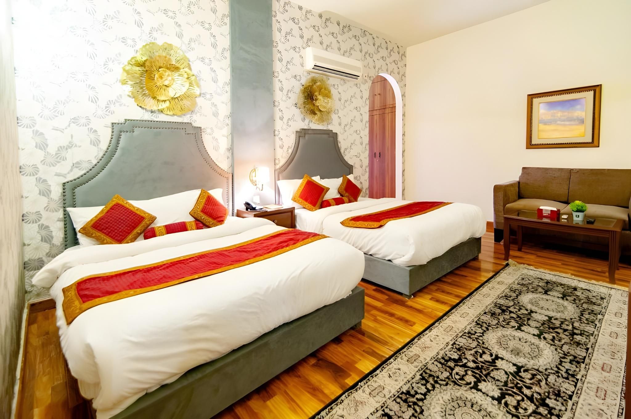 A hotel room with two beds, a sofa, a coffee table, and a painting on the wall.
