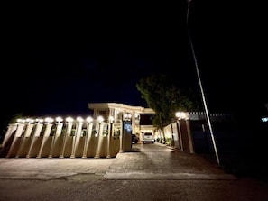A gated entrance with a number sign, a pathway leading to a building, and a vehicle parked inside. - Shelton Guest House (Islamabad)