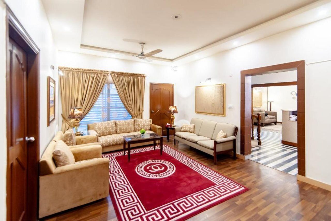 A spacious living room with a red patterned rug, two sofas, a coffee table, and a ceiling fan.