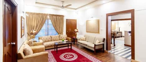 A spacious living room with a red patterned rug, two sofas, a coffee table, and a ceiling fan.