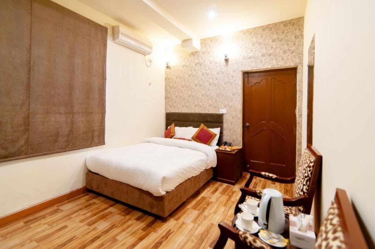 A hotel room with a bed, bedside table, and a wardrobe.
