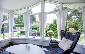 A conservatory with a curved ceiling, large windows, a round table, and a wicker chair. - Beautiful home in Hemmet with sauna (Hemmet)
