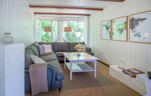 A cozy living room with a sectional sofa, a coffee table, and a bench. There are two lamps, a vase with flowers, and framed maps on the wall. - Beautiful home in Hemmet with sauna (Hemmet)