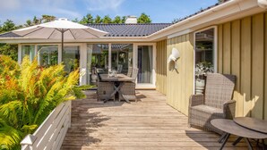 Una terrazza coperta all'aperto con un tavolo e sedie da pranzo, immersa nel verde.
