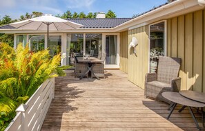 A covered outdoor deck with a dining table and chairs, surrounded by lush greenery. - Beautiful home in Hemmet with sauna (Hemmet)