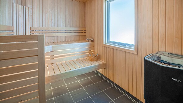 Una sauna con panche in legno, una finestra e una stufa sauna.