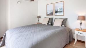 Una camera da letto con un letto grande, due comodini, una lampada e due quadri appesi al muro.
