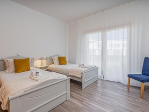 A hotel room with two beds, a chair, and a large window with sheer curtains. - Marina retreat with lake view (Lagos)