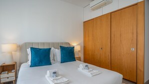 A hotel room with a bed, two bedside lamps, a wooden wardrobe, and an air conditioning unit. - Marina retreat with lake view (Lagos)