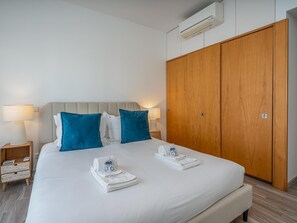 Ein Hotelzimmer mit einem Bett, zwei Nachttischlampen, einem Holzschrank und einer Klimaanlage.