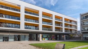 A multi-story building with balconies, a paved courtyard, and storefronts. - Marina retreat with lake view (Lagos)