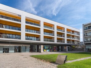 Ein mehrstöckiges Gebäude mit Balkonen, einem gepflasterten Innenhof und Geschäften.