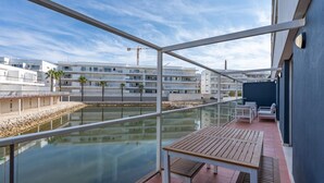 A balcony with a view of a calm water body, a wooden table, and a glass railing. - Marina retreat with lake view (Lagos)