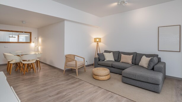 A modern living room with a grey sofa, a dining table with chairs, a floor lamp, and a large mirror. - Marina retreat with lake view (Lagos)