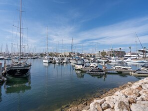 A marina with various boats docked, calm water, and a rocky shoreline. - Marina retreat with lake view (Lagos)