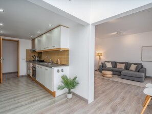 A modern apartment with a kitchen, a grey sofa, and a small potted plant. - Marina retreat with lake view (Lagos)