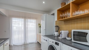 A modern kitchen with a washing machine, microwave, and a shelf with glassware. - Marina retreat with lake view (Lagos)