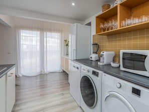 Eine moderne Küche mit Waschmaschine, Mikrowelle und einem Regal mit Gläsern.